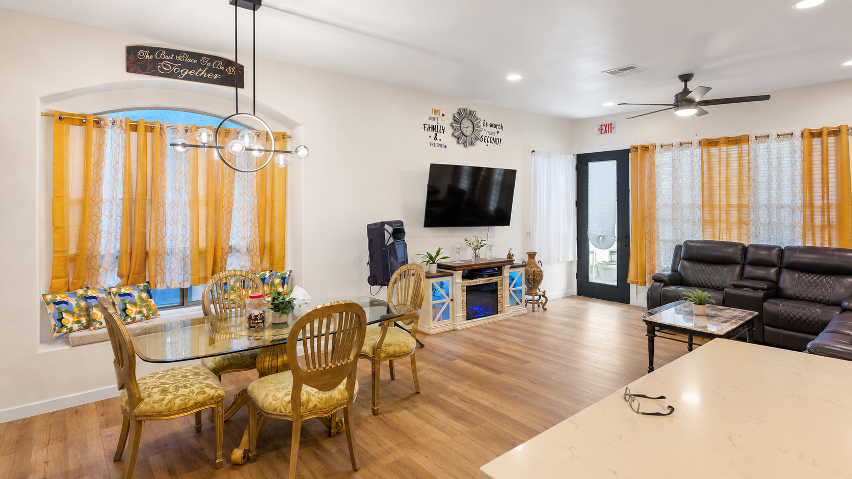Bright open living and dining space with seating, TV, and large windows